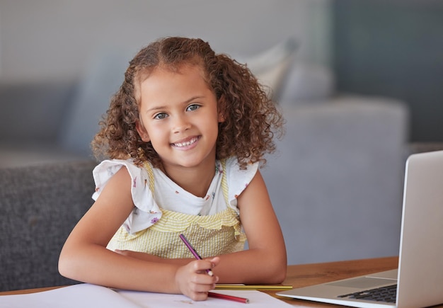 Foto kind mädchen lernen online-schreiben und lernen zu hause mit laptop auf dem tisch porträt eines glücklichen kreativen und jungen kindes mit einem lächeln für die bildung am computer und zeichnen im notizbuch mit farbstift