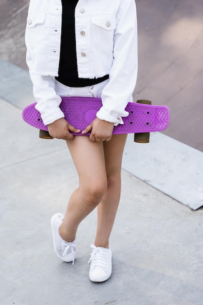 Kind Mädchen mit Penny Board Nahaufnahme Sportgeräte für Kinder Teenager mit Penny Board auf dem Spielplatz im Skatepark