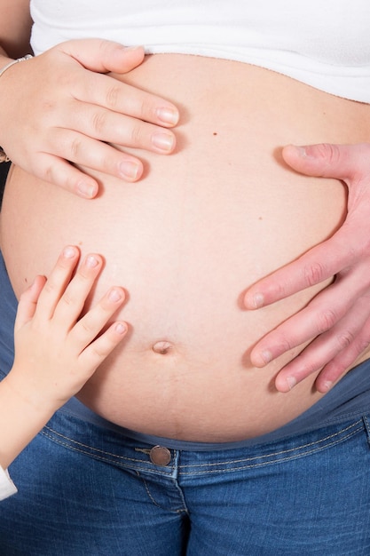 Kind, Mädchen oder Junge, das den Bauch der schwangeren Mutter mit Papa Vater berührt