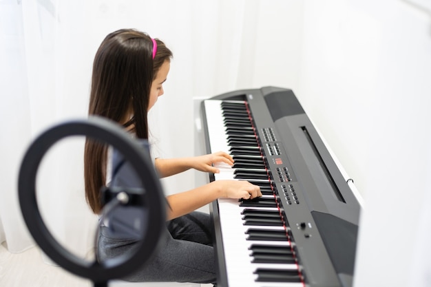 Kind Mädchen spielt Musik Keyboard Piano Instrument und dreht ein Video