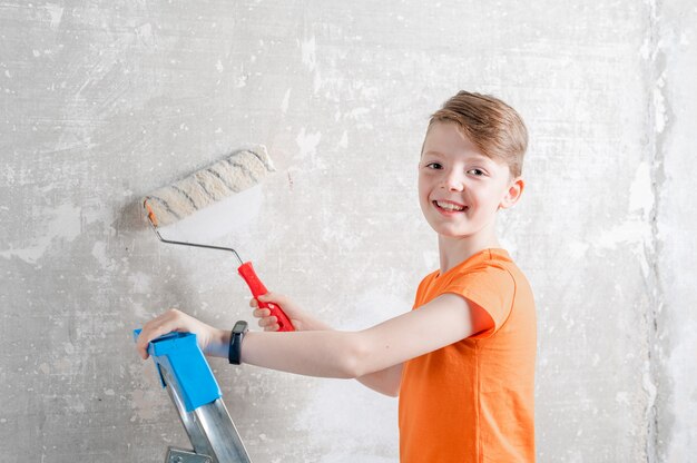 Kind malt eine blaue Wand mit einer Rollenreparatur