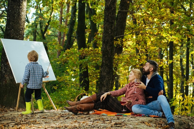 Kind malt mit Farben auf einer Staffelei im Herbstpark Kunstkonzept Malerei in der Natur beginnen