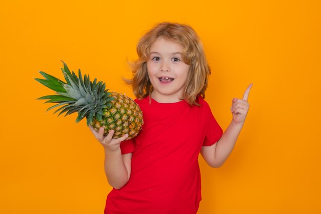 Kind mit Ananas im Studio Studioporträt eines niedlichen Kindes, das Ananas isoliert auf Gelb hält