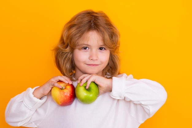 Kind mit Apfel im Studio Studioportrait des netten Kindes hält den Apfel lokalisiert auf gelbem Hintergrund