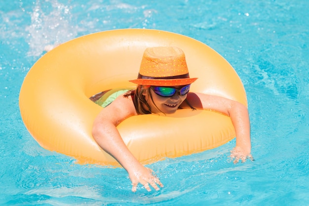 Kind mit aufblasbarem Ring im Schwimmbad Kid Boy schwimmen im Außenpool des tropischen Resorts Hot Summer Water Spielzeug und Schwimmer für Kinder