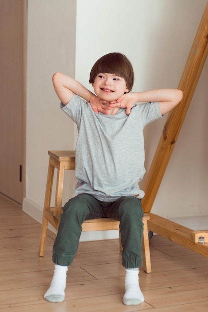 Kind mit Down-Syndrom sitzt zu Hause auf dem Stuhl