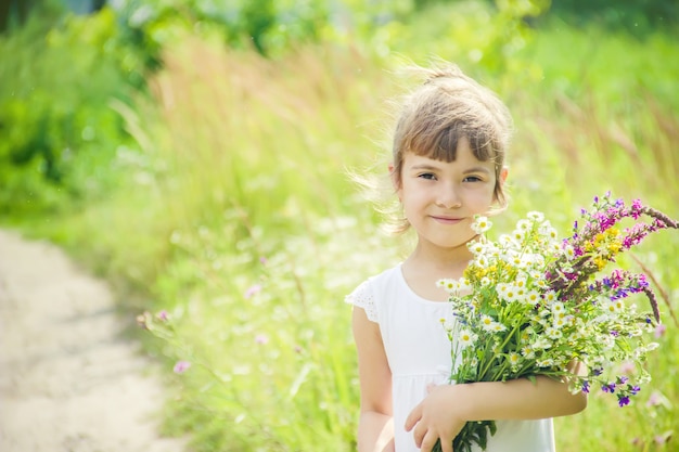 Kind mit einem Blumenstrauß von Wildblumen. Tiefenschärfe. Natur.