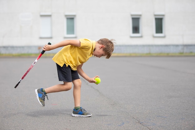 Kind mit einem Tennisschläger und einem Ball Jungentennisspieler Schuljunge treibt Sport