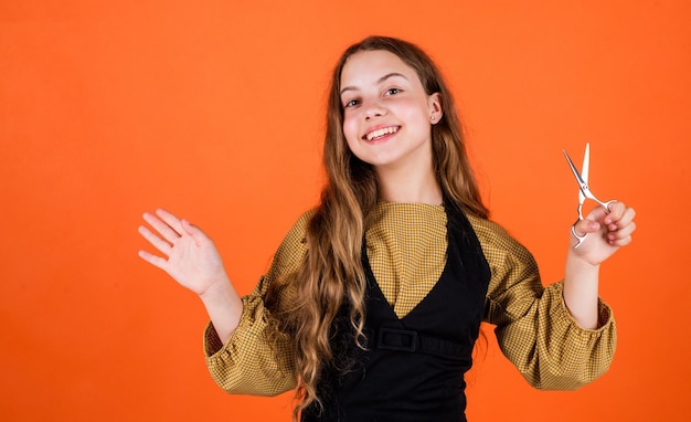 Kind mit einer Schere will Haare schneiden Mädchen im Friseursalon Teenager beim Haareschneiden Nettes Mädchen, das sich mit einer Schere die Haare schneidet Kind wird in der Friseurform getrimmt, folgt Ihnen