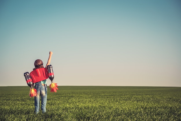 Kind mit Jetpack im Freien Kind spielt im grünen Frühlingsfeld