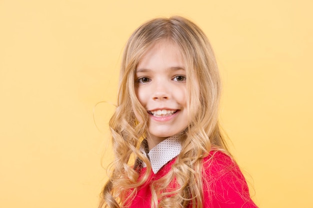 Kind mit lockigem blondem Haar auf orangefarbenem Hintergrund