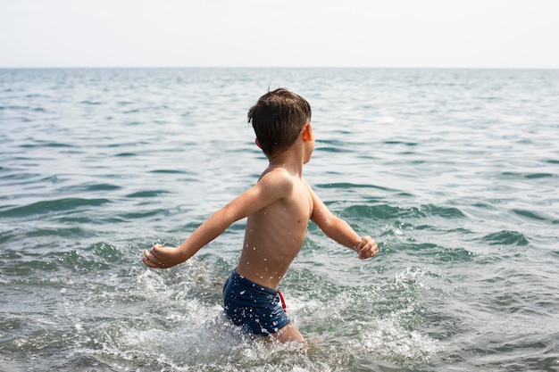 Foto kind mit mittlerem schuss, das im wasser spielt