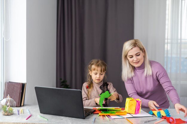 Kind mit Mutter hat Spaß beim Ausschneiden von Scherenpapier im Vorschulalter. Mutter und Tochter machen Papierhandwerk