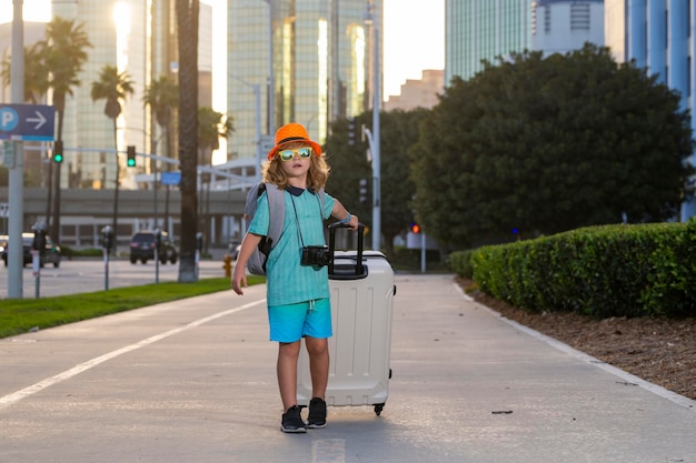 Kind mit Reisekoffer im Urlaub Kinderreise- und Abenteuerkonzept Kinderjunge, der in den Urlaub fährt und Gepäckreisetasche im Freien hält