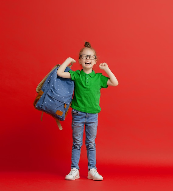 Kind mit Rucksack auf farbigem Hintergrund