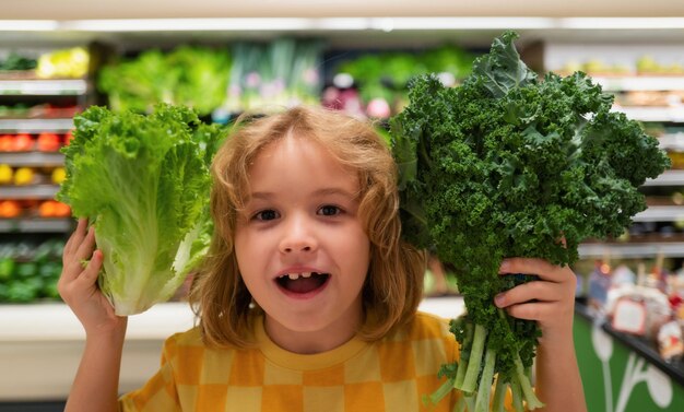 Kind mit Salat-Mangold-Gemüse Kleines Kind wählt Lebensmittel im Lebensmittelgeschäft oder Supermarkt aus