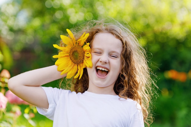 Kind mit Sonnenblumen in seiner Hand zeigen weiße Zähne