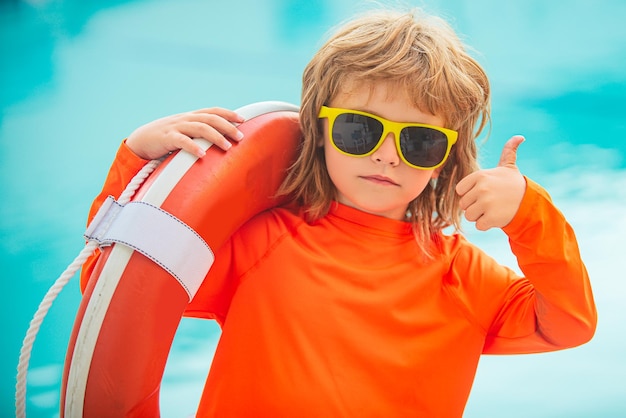 Kind mit Sonnenbrille am Strand Kinderjunge Rettungsschwimmer zeigen Daumen hoch wie ok