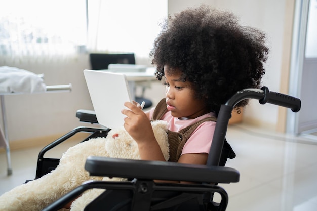 Kind mit Tablet und sitzt im Rollstuhl. Gesundheit und Wohlbefinden eines Patienten im Krankenhaus.