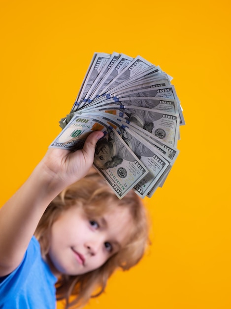 Kind mit vielen hundert Dollar isoliert auf gelbem Hintergrund