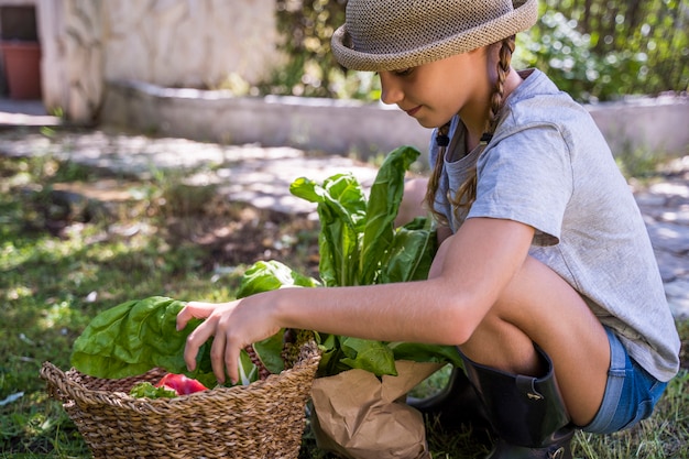 Kind mit Weidenhut in der Sommerzeit mit Lebensmitteln im Weidenkorb