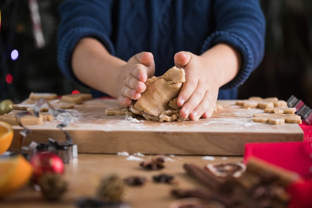 Kind rollt Teig für Weihnachtsplätzchen aus