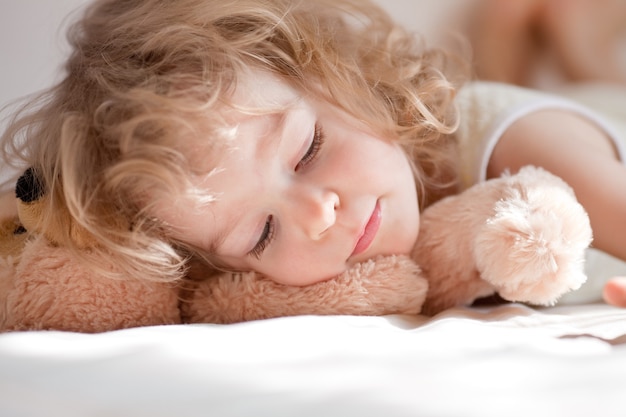 Kind schläft im Bett mit Teddy