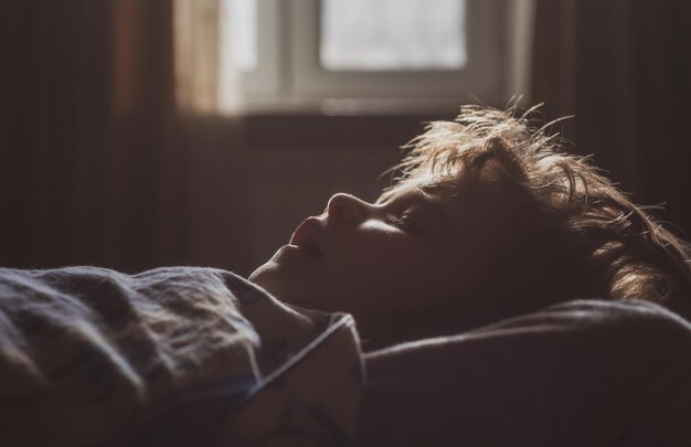 Kind schläft im Bett. Morgenlichter.