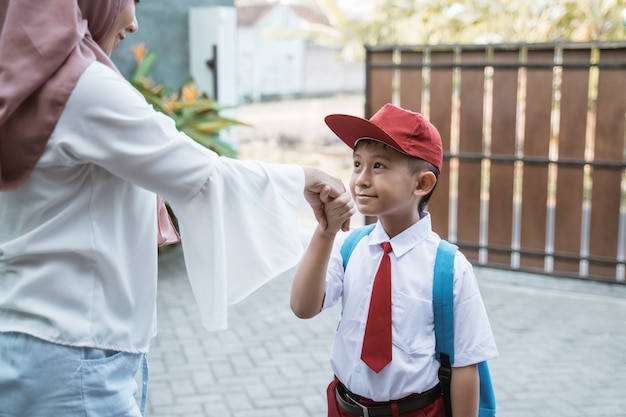 Kind schüttelt Hand und küsst Hand vor der Schule