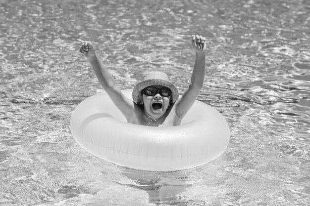 Kind schwimmt auf dem Ring, der im blauen Swimmingpool schwimmt Konzept der aufblasbaren Ringruhe für Kinder