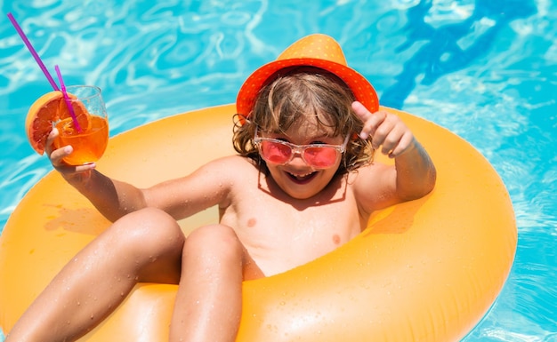 Kind schwimmt im Pool Kind entspannt sich im Pool trinken Sommercocktail süßer kleiner Junge entspannt sich mit