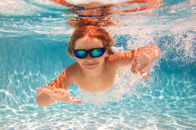 Kind schwimmt im Pool unter Wasser. Junge schwimmt unter Wasser im Meer. Kind spielt und taucht im Schwimmbad