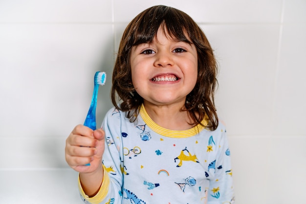 Kind sehr fröhlich nach dem Zähneputzen mit einer Zahnbürste mit Pyjama vor dem Schlafengehen