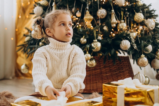 Kind sitzt unter dem Weihnachtsbaum