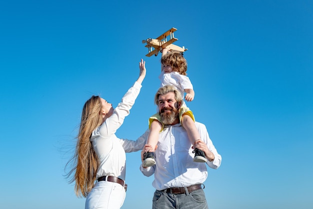 Kind Sohn mit Vater und Mutter Mutter Vater und Kind Junge mit Spielzeugflugzeug Urlaub und Zweisamkeit Kindertag Kind spielt mit Spielzeugflugzeug und träumt Zukunftskonzept von Träumen und Reisen