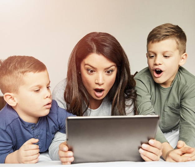 Kind, Sohn, Mutter, Familie, überrascht, schockiert, erstaunt, spielende Tablet-Bett-Technologie für Kinder in der Kindheit