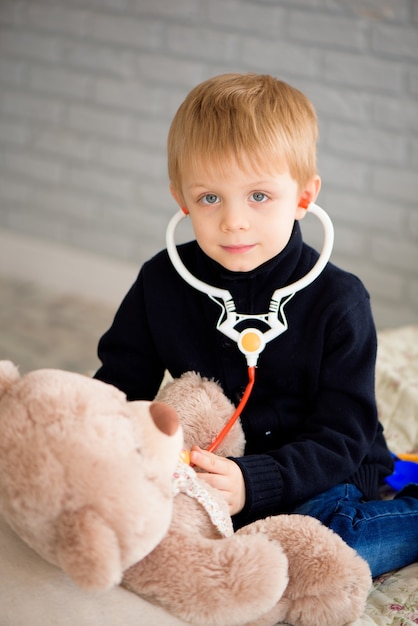 Kind spielender Arzt mit einem Spielzeug. Kinderarzt für Kinder im Vorschul- und Kindergarten. Konzept für Kinder, Gesundheitswesen und Menschen.