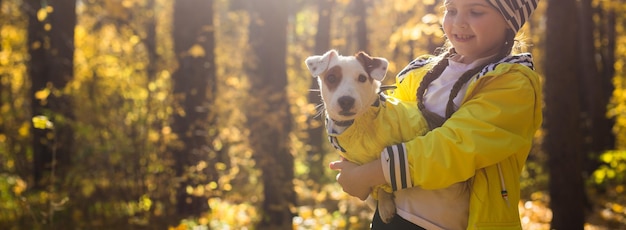 Kind spielt mit Jack Russell Terrier im herbstlichen Wald. Herbstspaziergang mit Hund, Kindern und Haustierkonzept.