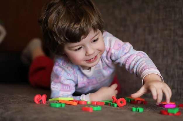 Kind spielt mit kleinen Spielsachen auf der Couch im Zimmer