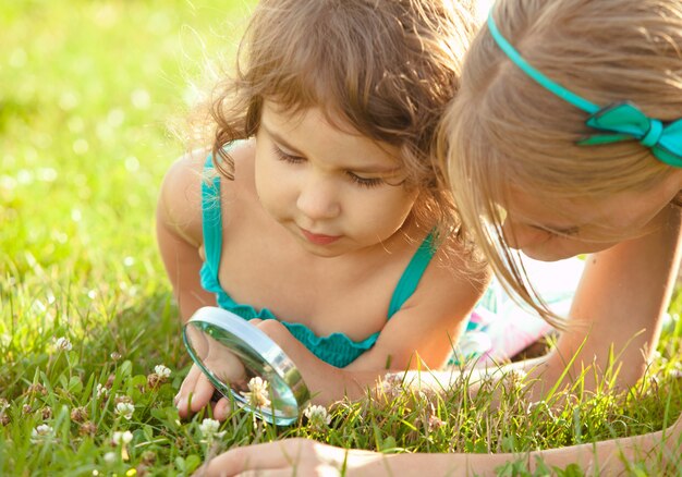 Kind spielt mit Lupe im Garten