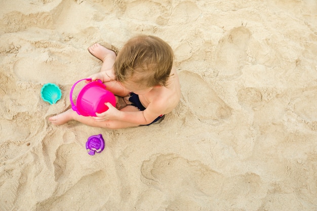 Kind spielt mit Spielzeug auf Sand