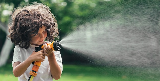 Kind spielt mit Wasser im Hinterhof im Garten