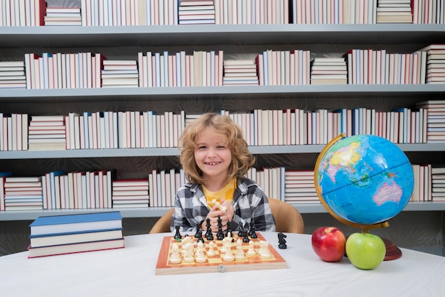 Kind spielt Schach in der Schule Kluges konzentriertes und denkendes Kind spielt Schach Kind Junge entwickelt sich