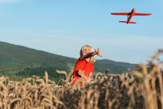 Kind startet rotes Modellflugzeug in den Himmel Glückliche unbeschwerte Kindheit Spielzeugflugzeug gegen blauen Himmel