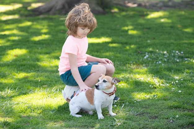 Kind streichelt Hund Junge und Hund auf dem Gras zusammen Fröhlicher Junge umarmt sein Haustier Kind streichelt Hund