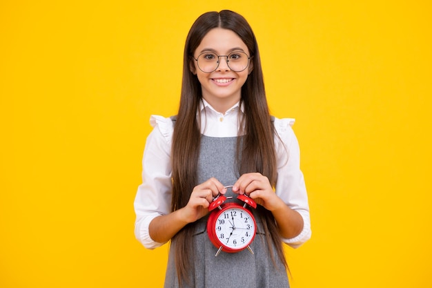 Kind Student Mädchen mit Uhr isoliert auf gelbem Hintergrund Kind zurück zur Schule Bildung und Zeitkonzept Glückliches Gesicht positive und lächelnde Emotionen von Teenager-Mädchen