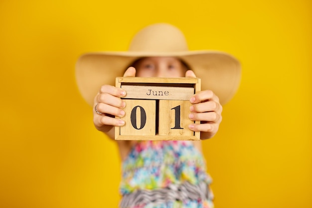 Kind Teenager Mädchen im Badeanzug und Strohhut halten Holzkalender in der Hand