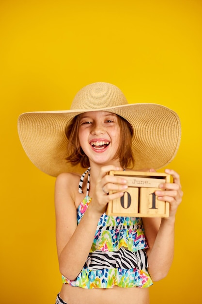 Kind Teenager Mädchen im Badeanzug und Strohhut halten Holzkalender in der Hand