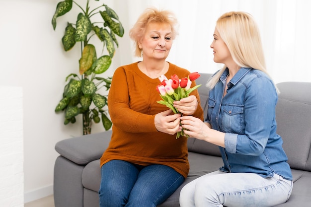 Kind Tochter gratuliert Mutter und gibt einen Blumenstrauß Tulpen.