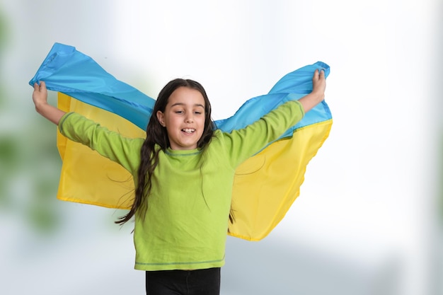 Kind trägt flatternde blaue und gelbe Flagge der Ukraine isoliert auf weiß. Unabhängigkeitstag der Ukraine. Flagge Tag. Tag der Verfassung. Mädchen in traditioneller Stickerei mit Flagge der Ukraine